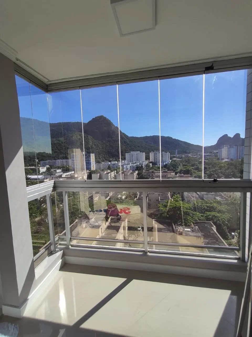 Varanda envidraçada com insulfilm aplicado e vista para as montanhas da Zona Oeste do Rio